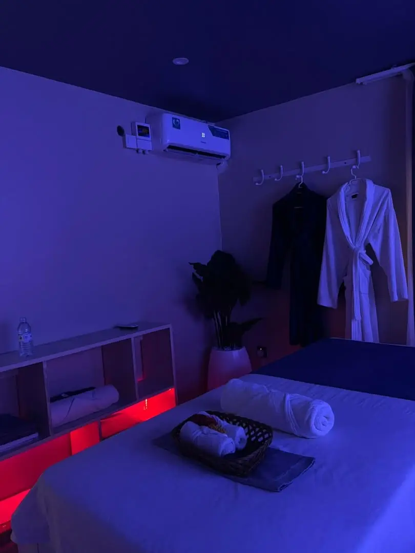 Rolled towels on the table, with robes hanging and a plant in the corner